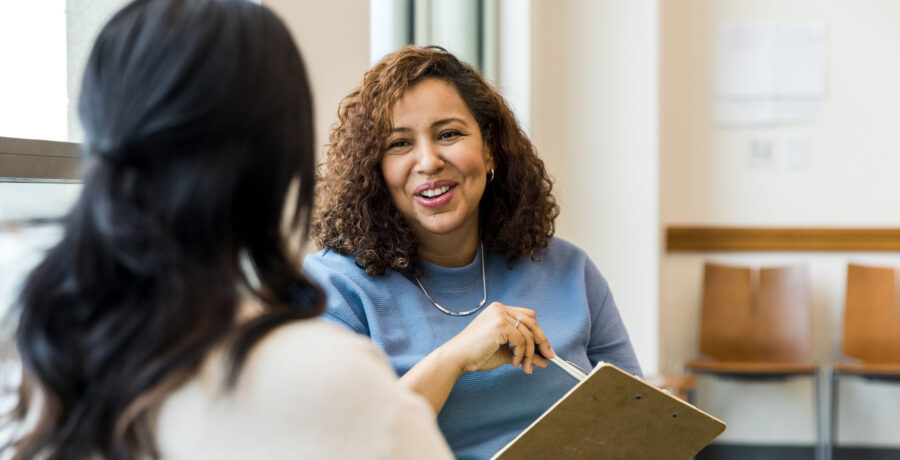 Counseling session with two people seated, the counselor is facing the camera and smiling